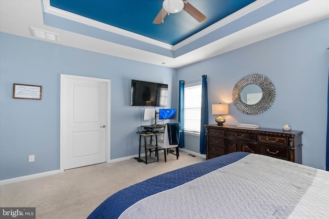 carpeted bedroom with a tray ceiling, ceiling fan, and crown molding