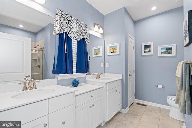 bathroom featuring tile patterned flooring, vanity, toilet, and a shower with door