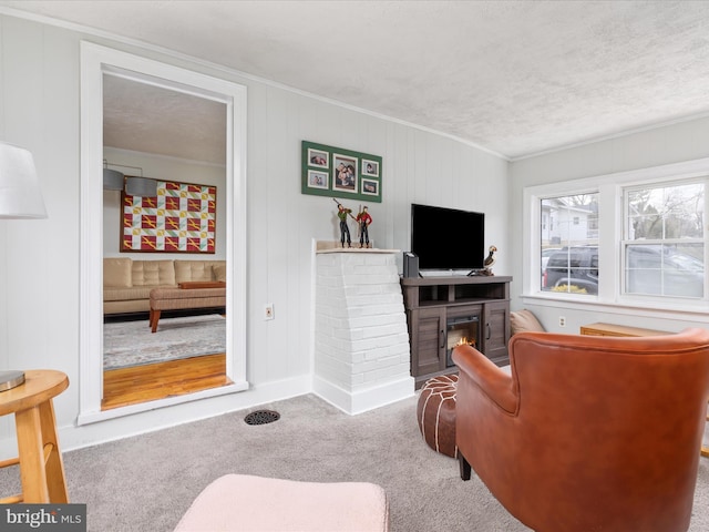 carpeted living room with a fireplace, ornamental molding, and a textured ceiling