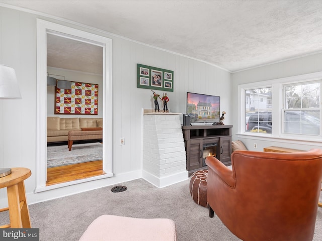 living room featuring crown molding, carpet, a textured ceiling, and a fireplace