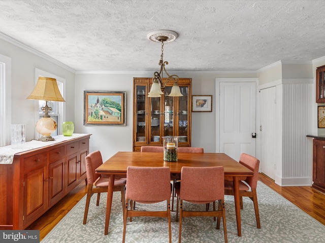 dining space featuring ornamental molding, light hardwood / wood-style flooring, and a textured ceiling