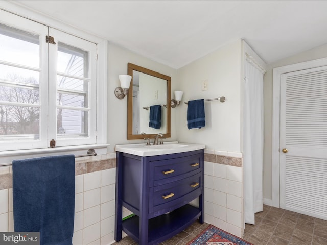 bathroom featuring tile walls, vanity, and lofted ceiling