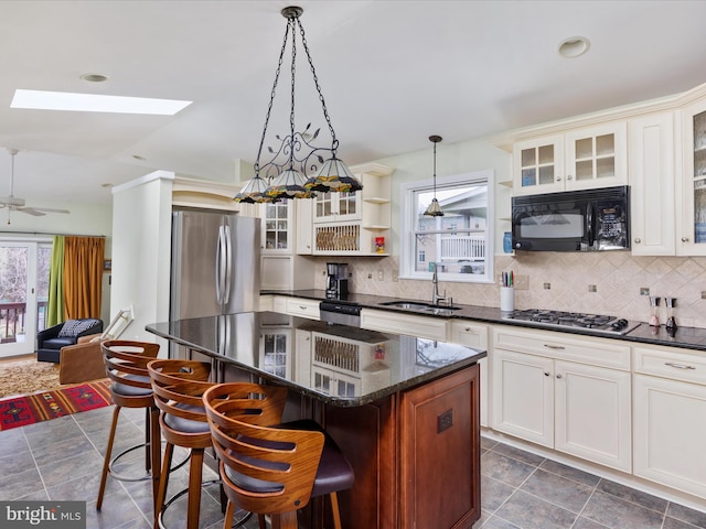 kitchen with sink, stainless steel appliances, a kitchen breakfast bar, a kitchen island, and decorative light fixtures