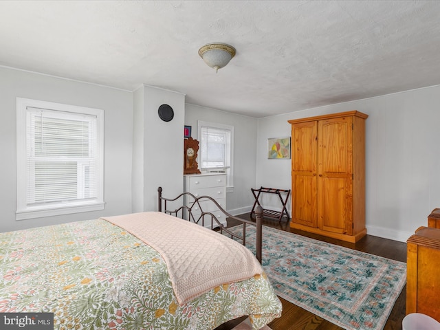 bedroom featuring dark hardwood / wood-style floors, multiple windows, and a textured ceiling