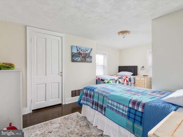 bedroom with a textured ceiling and dark hardwood / wood-style flooring