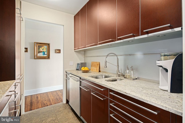 kitchen featuring stainless steel dishwasher, light stone counters, and sink