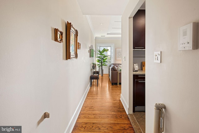 hallway featuring crown molding, a tray ceiling, and dark wood-type flooring