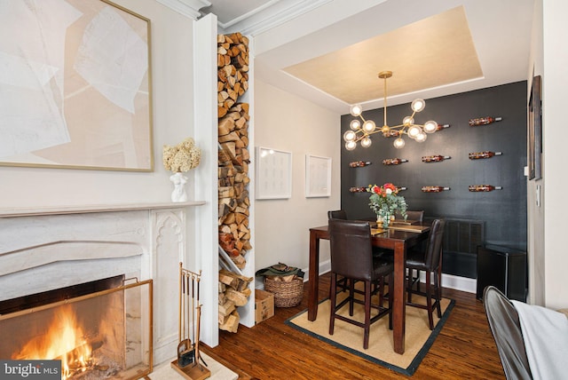 dining space with dark hardwood / wood-style floors, ornamental molding, and an inviting chandelier