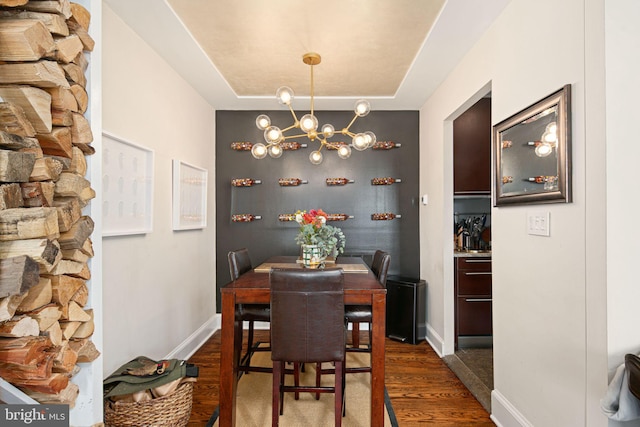 dining room with a chandelier, dark hardwood / wood-style floors, and a raised ceiling