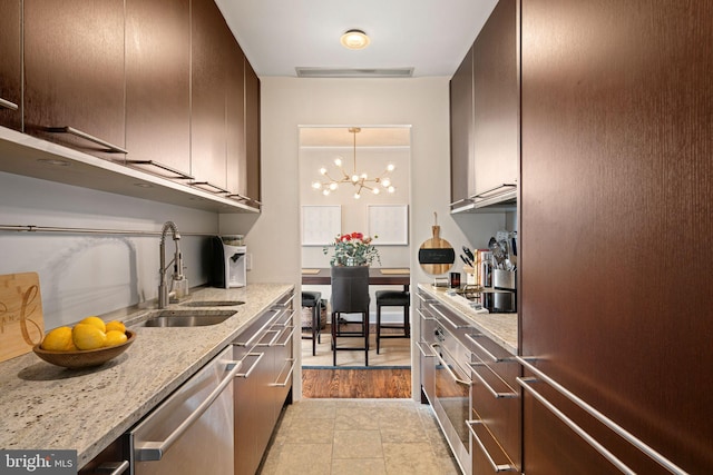 kitchen featuring sink, a notable chandelier, light stone counters, dark brown cabinetry, and stainless steel appliances