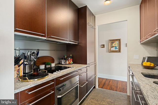 kitchen with light stone countertops, black electric stovetop, and oven