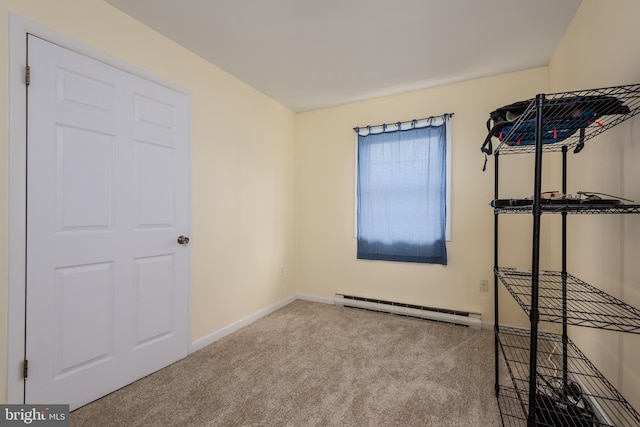 carpeted empty room featuring a baseboard heating unit