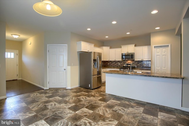 kitchen featuring sink, dark stone countertops, appliances with stainless steel finishes, tasteful backsplash, and white cabinetry