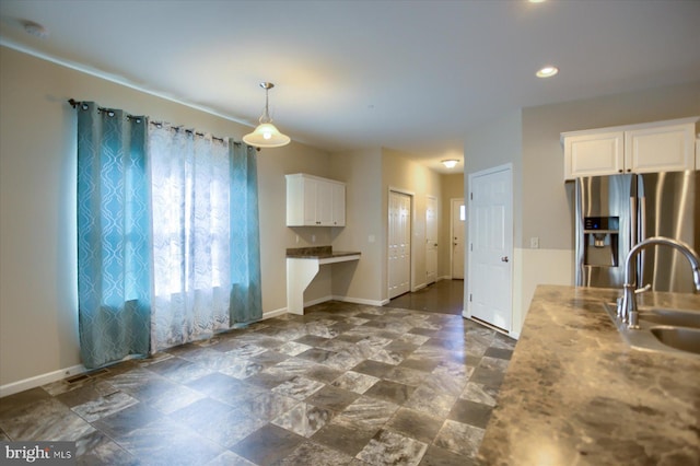 kitchen with white cabinetry, stainless steel fridge, sink, and decorative light fixtures