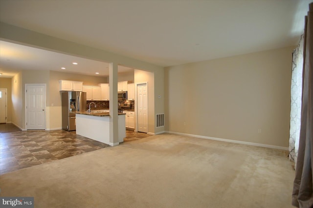 unfurnished living room with light carpet and sink