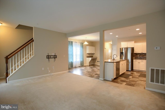 kitchen with sink, pendant lighting, light carpet, white cabinets, and appliances with stainless steel finishes