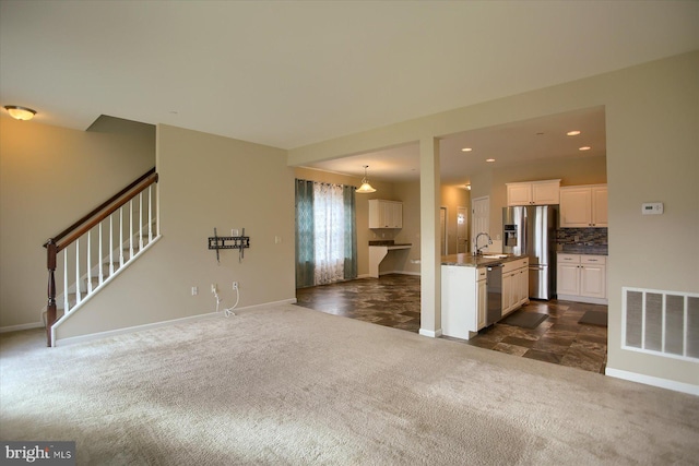 unfurnished living room featuring dark colored carpet and sink