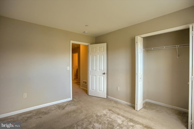 unfurnished bedroom featuring light carpet and a closet