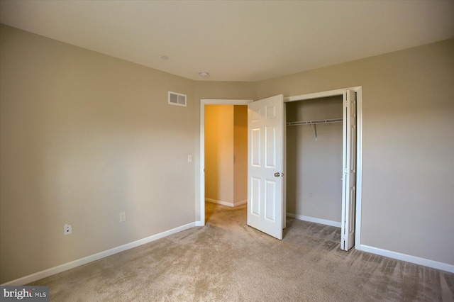 unfurnished bedroom with a closet and light colored carpet