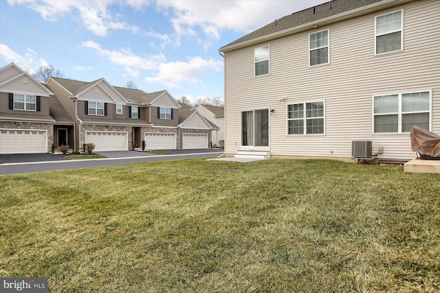 exterior space featuring a garage, a lawn, and central air condition unit