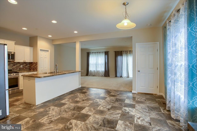 kitchen featuring white cabinetry, sink, decorative backsplash, a center island with sink, and appliances with stainless steel finishes