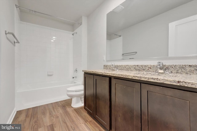 full bathroom featuring hardwood / wood-style floors, tiled shower / bath combo, toilet, and vanity