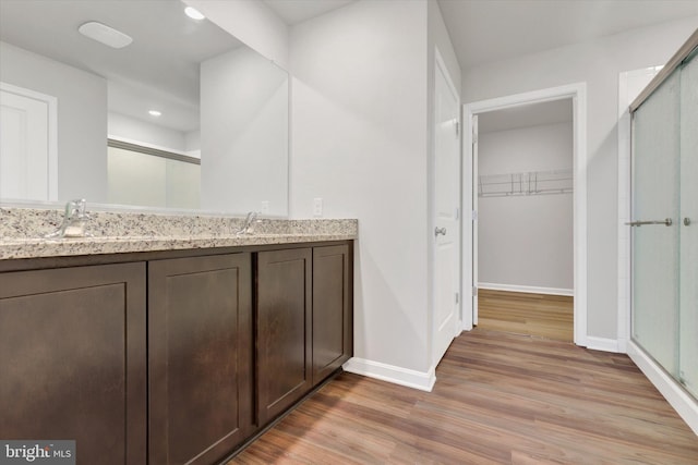 bathroom featuring walk in shower, vanity, and hardwood / wood-style flooring