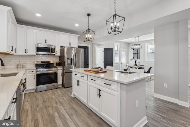 kitchen featuring white cabinets, decorative light fixtures, and stainless steel appliances