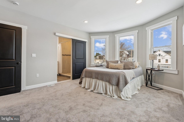 bedroom featuring connected bathroom and light colored carpet