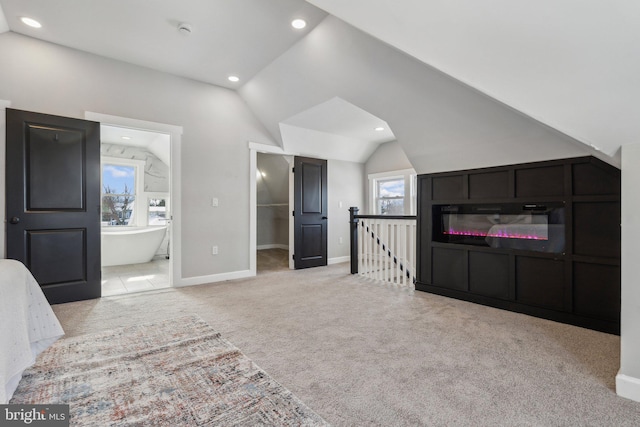 bedroom with ensuite bathroom, a spacious closet, light carpet, and multiple windows