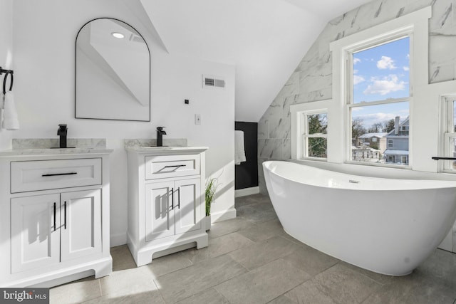 bathroom featuring vanity, a tub to relax in, tile walls, and lofted ceiling