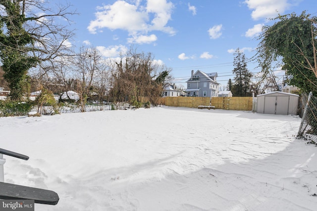 yard layered in snow featuring a shed