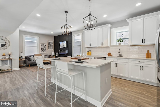 kitchen featuring white cabinets, decorative light fixtures, a center island, and light hardwood / wood-style flooring