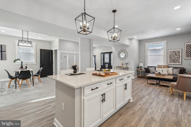 kitchen featuring a center island, light hardwood / wood-style floors, white cabinetry, and hanging light fixtures