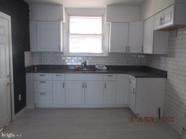 kitchen featuring tasteful backsplash, white cabinetry, and sink