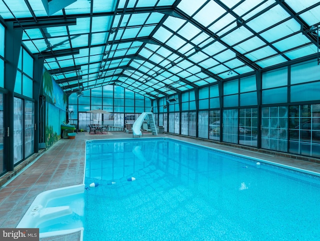 view of pool featuring glass enclosure, a patio area, and a water slide