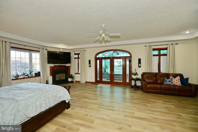 bedroom with french doors, light wood-type flooring, a textured ceiling, and ceiling fan