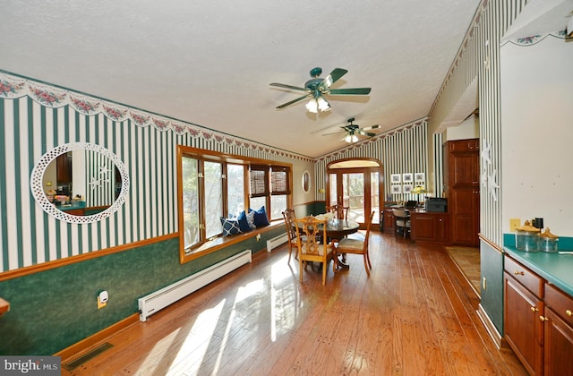 dining room featuring ceiling fan, light hardwood / wood-style floors, a textured ceiling, and a baseboard heating unit