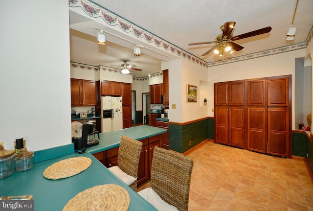 kitchen featuring ceiling fan, white refrigerator with ice dispenser, and a textured ceiling