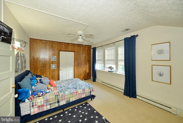 carpeted bedroom featuring a textured ceiling, baseboard heating, ceiling fan, wooden walls, and lofted ceiling