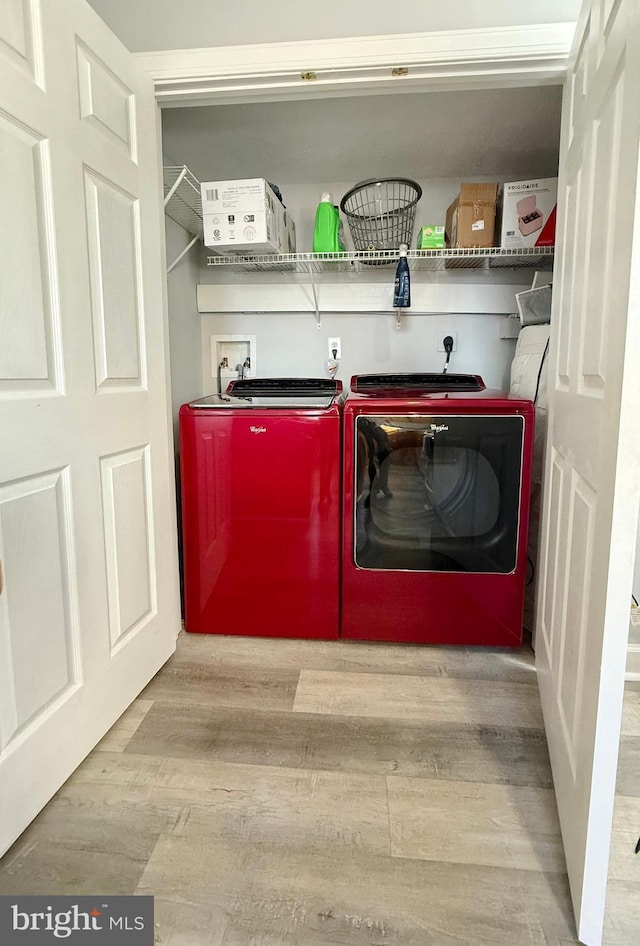 clothes washing area with light hardwood / wood-style flooring and washing machine and clothes dryer