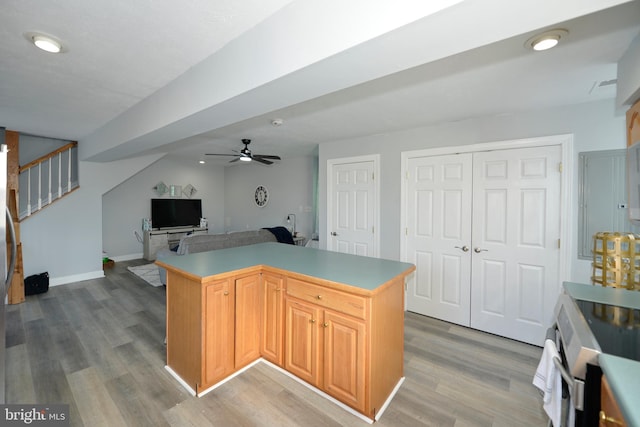 kitchen featuring hardwood / wood-style floors, ceiling fan, stove, and light brown cabinetry