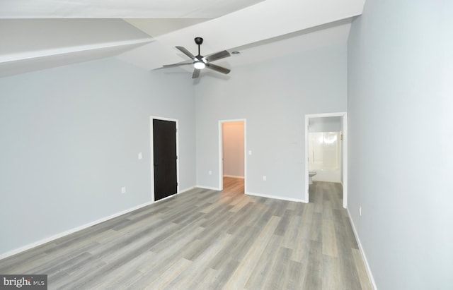 unfurnished bedroom featuring connected bathroom, light hardwood / wood-style flooring, and high vaulted ceiling