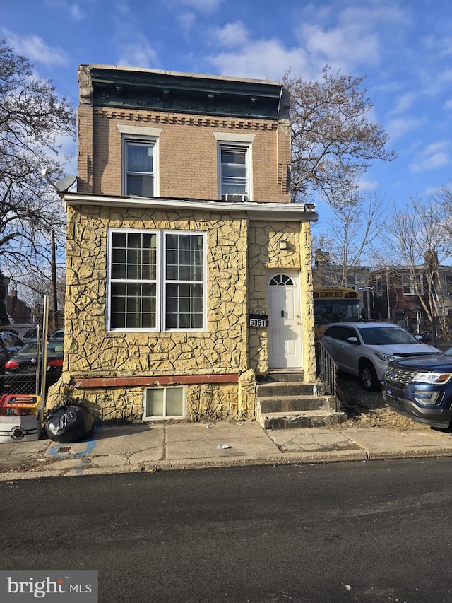 view of front facade featuring entry steps, stone siding, and brick siding