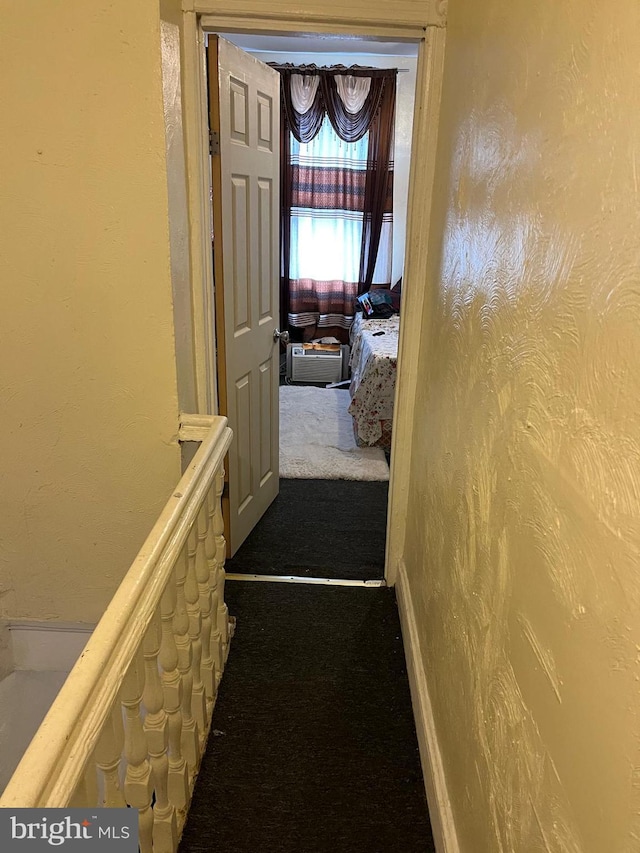 hall with dark colored carpet and a textured wall