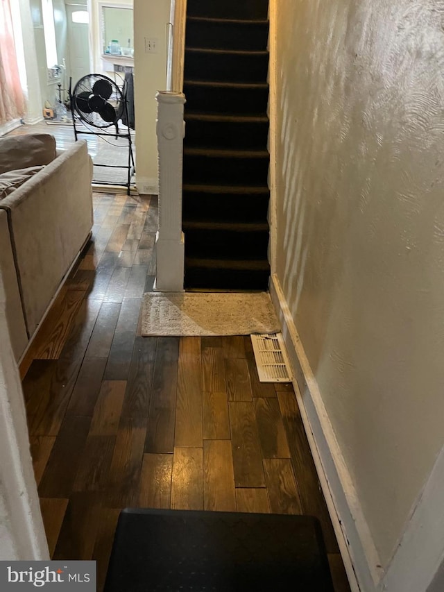stairs with visible vents, baseboards, and hardwood / wood-style floors