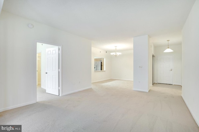 spare room with light carpet and a notable chandelier