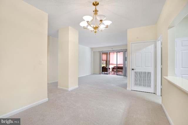 carpeted spare room featuring an inviting chandelier