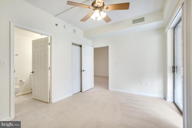 unfurnished bedroom featuring light carpet, ceiling fan, and ensuite bathroom