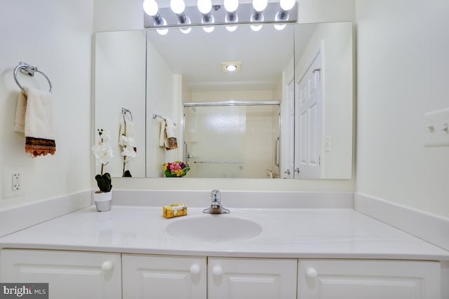 bathroom featuring vanity and a shower with door